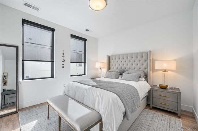 bedroom with visible vents, baseboards, and wood finished floors