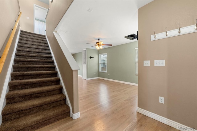 staircase featuring wood-type flooring and ceiling fan