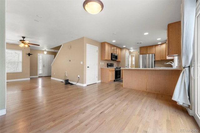 kitchen featuring ceiling fan, sink, stainless steel appliances, kitchen peninsula, and light hardwood / wood-style floors