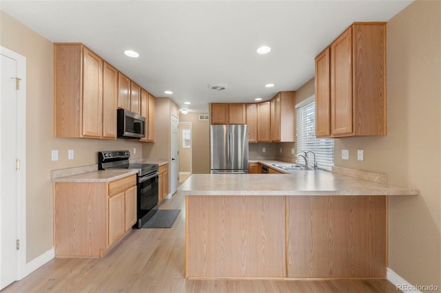 kitchen with kitchen peninsula, light wood-type flooring, stainless steel appliances, sink, and light brown cabinets