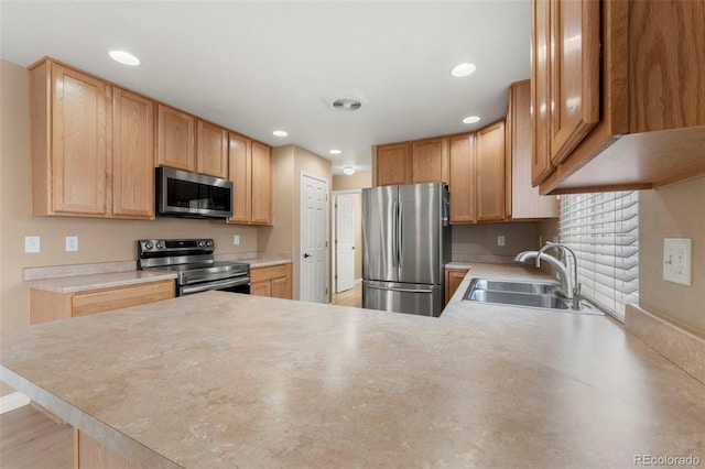 kitchen with light brown cabinetry, kitchen peninsula, sink, and appliances with stainless steel finishes