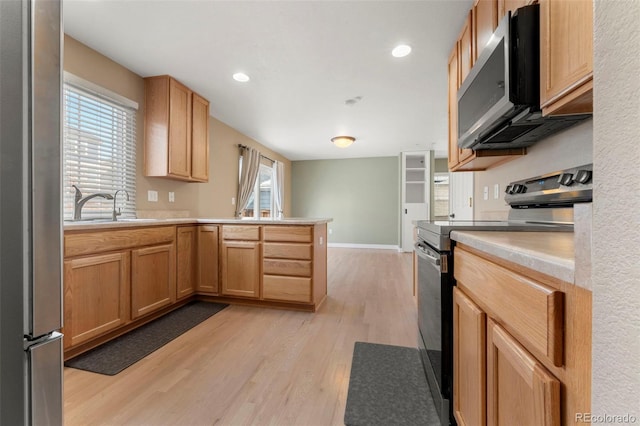 kitchen with sink, light brown cabinetry, appliances with stainless steel finishes, light hardwood / wood-style floors, and kitchen peninsula