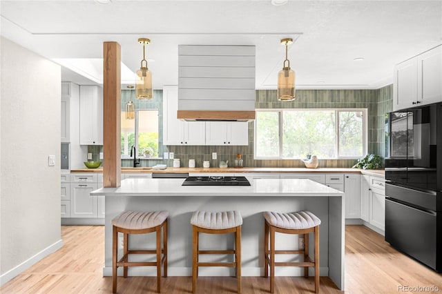 3089 S Jasmine St, Denver, CO 80222 - kitchen with black appliances, ventilation hood, tasteful backsplash, a breakfast bar, and light countertops
