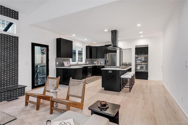 interior space with a kitchen island, island range hood, tasteful backsplash, a kitchen breakfast bar, and stainless steel fridge with ice dispenser