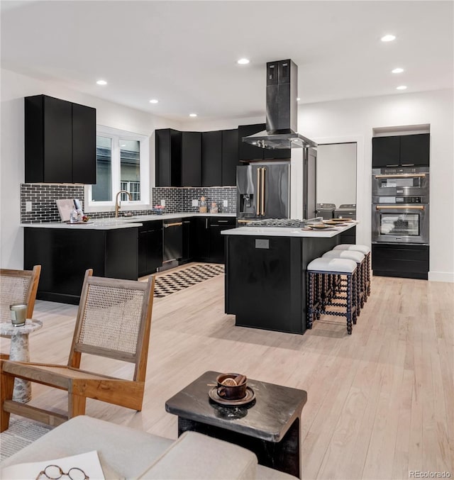 kitchen featuring a breakfast bar area, stainless steel appliances, a center island, tasteful backsplash, and island exhaust hood