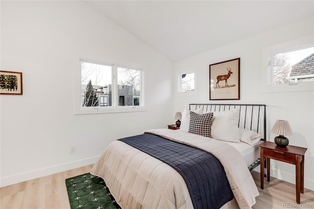 bedroom with lofted ceiling, hardwood / wood-style floors, and multiple windows