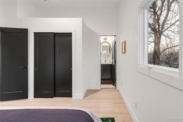 bedroom featuring ensuite bath and light hardwood / wood-style floors