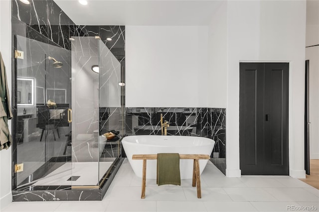 bathroom with tile walls and independent shower and bath