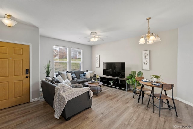 living room featuring ceiling fan with notable chandelier and wood-type flooring