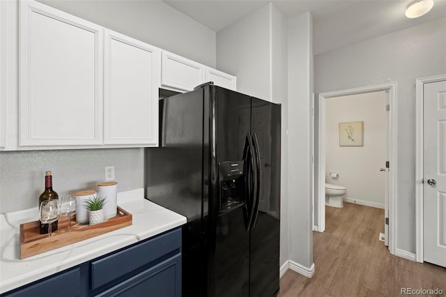 kitchen with white cabinets, light hardwood / wood-style floors, black refrigerator with ice dispenser, and blue cabinets