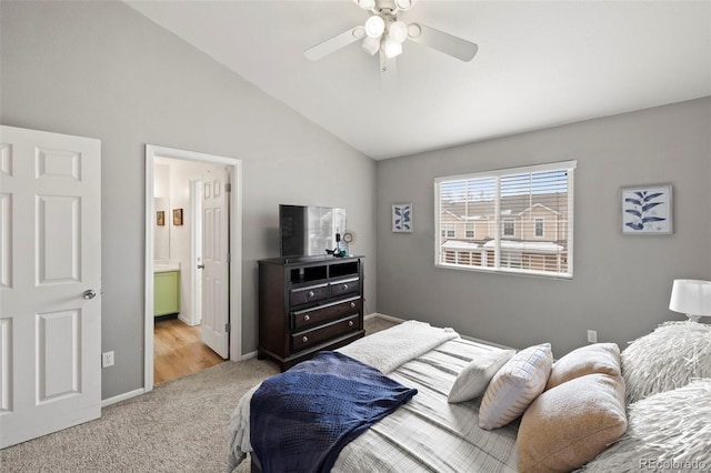 carpeted bedroom with ensuite bath, ceiling fan, and vaulted ceiling