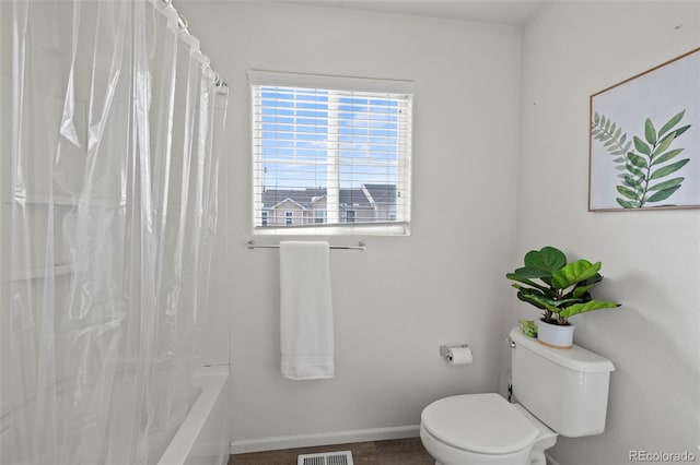 bathroom with hardwood / wood-style flooring, shower / bath combo, and toilet