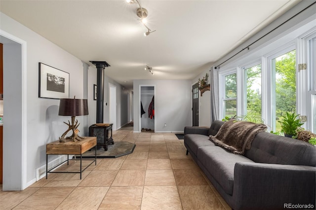 living room with a wood stove, light tile patterned floors, and track lighting