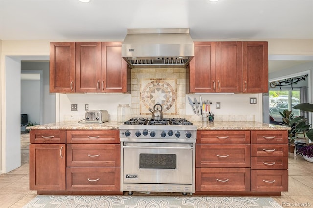 kitchen with light tile patterned floors, exhaust hood, designer range, light stone countertops, and tasteful backsplash