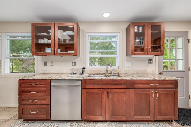 kitchen featuring a wealth of natural light, sink, light stone counters, and dishwasher