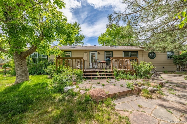 rear view of house featuring a lawn and a wooden deck