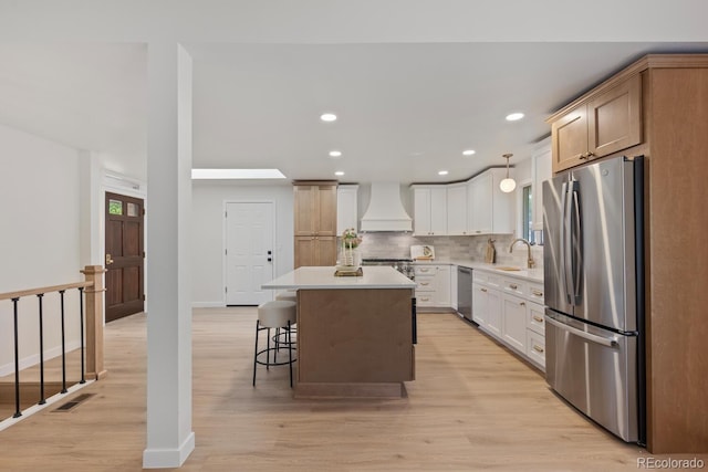 41 Eagle Dr, Littleton, CO 80123 - kitchen featuring freestanding refrigerator, premium range hood, a sink, decorative backsplash, and a breakfast bar area