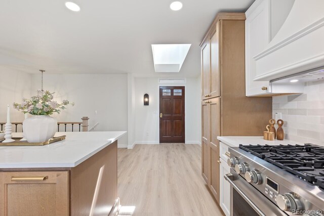 41 Eagle Dr, Littleton, CO 80123 - kitchen featuring premium range hood, gas range, a skylight, decorative backsplash, and light wood-type flooring