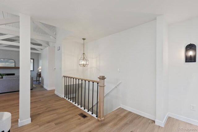 41 Eagle Dr, Littleton, CO 80123 - hall with an upstairs landing, wood finished floors, baseboards, beam ceiling, and a chandelier