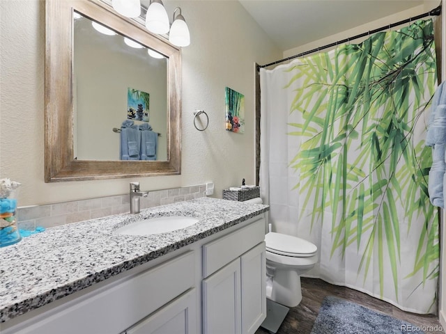 bathroom featuring wood finished floors, toilet, vanity, a textured wall, and a shower with shower curtain