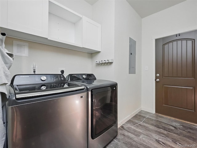 washroom featuring cabinet space, washing machine and dryer, wood finished floors, electric panel, and baseboards