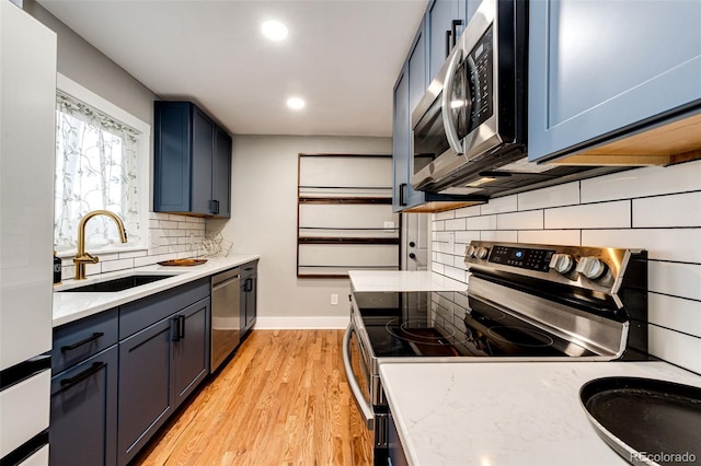 1945 Yosemite St, Denver, CO 80220 - kitchen featuring appliances with stainless steel finishes, a sink, backsplash, light wood-style floors, and baseboards