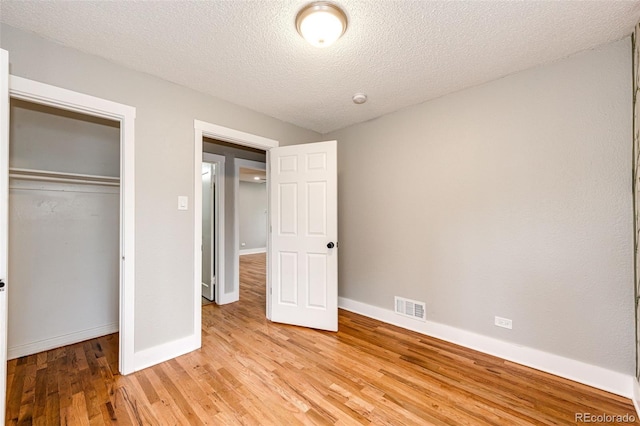 1945 Yosemite St, Denver, CO 80220 - unfurnished bedroom with light wood-style floors, baseboards, a closet, and a textured ceiling