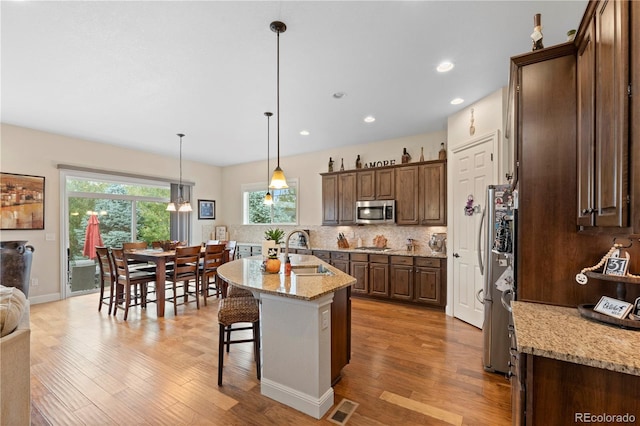 15003 W 63rd Ave, Arvada, CO 80403 - kitchen with appliances with stainless steel finishes, light wood-style floors, tasteful backsplash, a kitchen bar, and recessed lighting