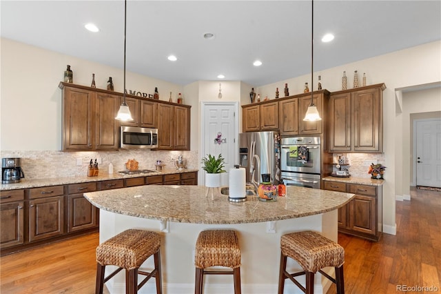 15003 W 63rd Ave, Arvada, CO 80403 - kitchen featuring stainless steel appliances, a kitchen breakfast bar, backsplash, light stone counters, and recessed lighting