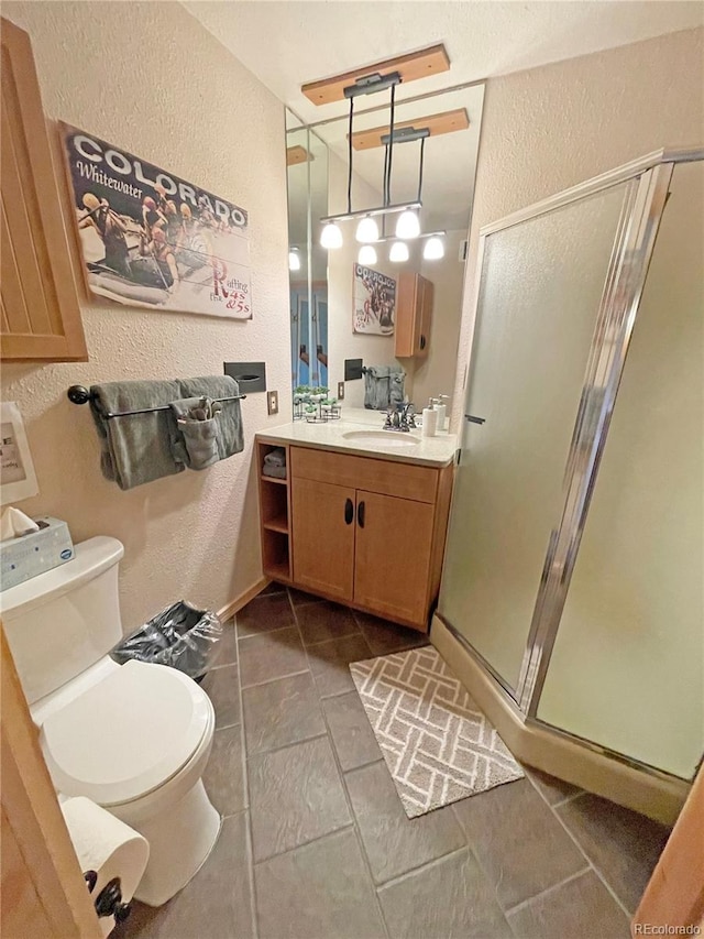 bathroom featuring vanity, a shower with shower door, and toilet