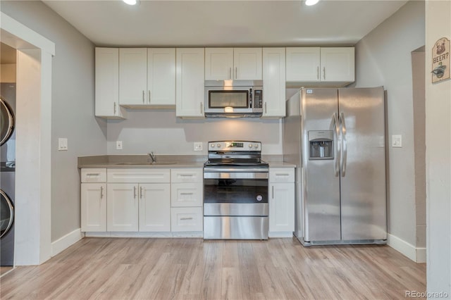 6660 Locust St, Commerce City, CO 80022 - kitchen featuring stacked washer and clothes dryer, appliances with stainless steel finishes, and white cabinetry