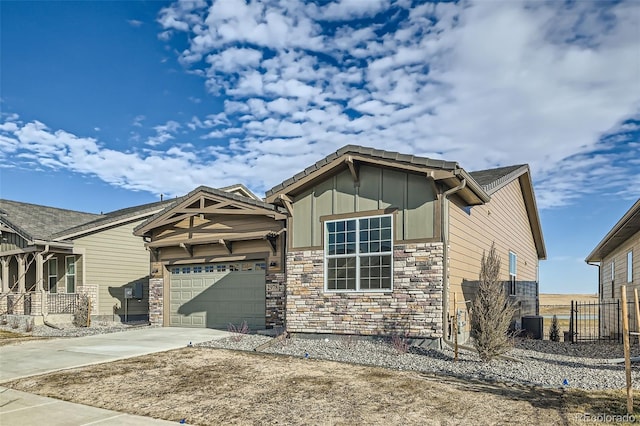 craftsman-style home with an attached garage, fence, concrete driveway, stone siding, and board and batten siding