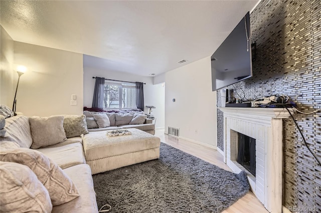 3550 S Harlan St Unit 311, Denver, CO 80235 - living area with light wood-style flooring, a brick fireplace, and baseboards