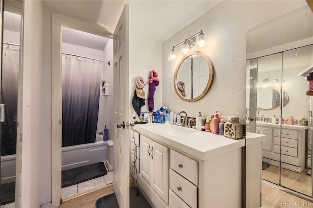 3550 S Harlan St Unit 311, Denver, CO 80235 - bathroom with vanity, shower / bathtub combination with curtain, a textured wall, and wood finished floors