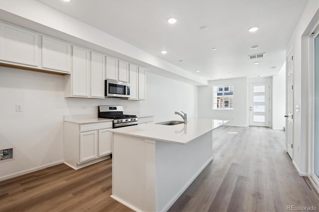 kitchen with an island with sink, light wood-style flooring, a sink, stainless steel appliances, and white cabinets