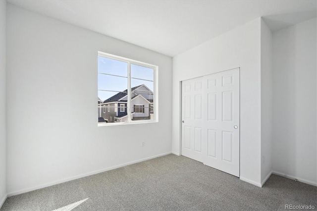 unfurnished bedroom featuring carpet, baseboards, and a closet