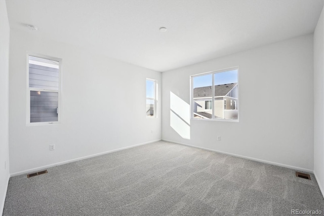 carpeted spare room featuring visible vents and baseboards