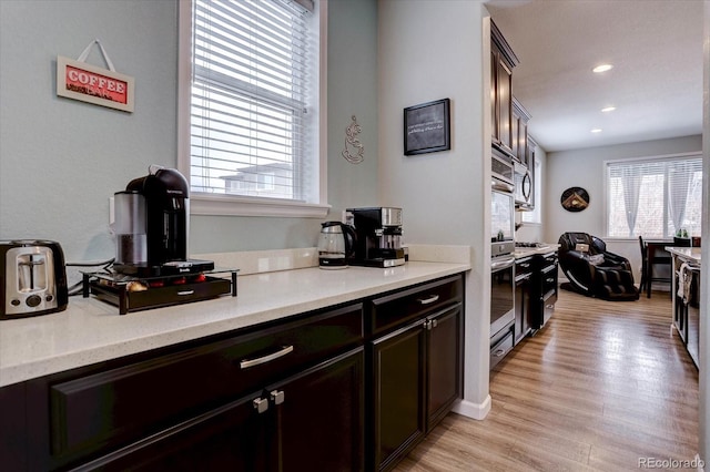 kitchen featuring dark brown cabinets, stainless steel double oven, and light wood-type flooring