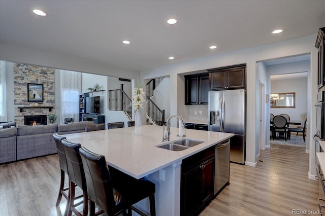 kitchen with sink, a breakfast bar area, stainless steel refrigerator with ice dispenser, and a center island with sink