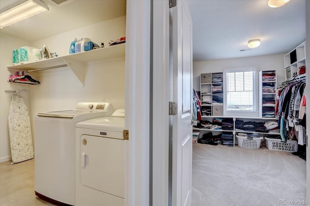 clothes washing area featuring light colored carpet and washer and dryer