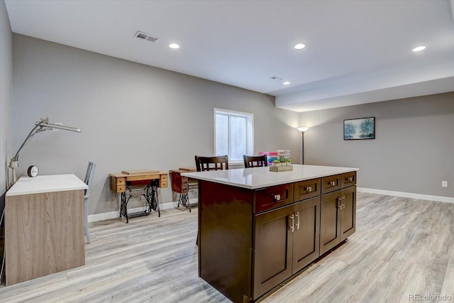 kitchen with light hardwood / wood-style flooring, dark brown cabinets, and a center island