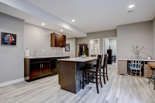 kitchen with black dishwasher, sink, a kitchen island, and light hardwood / wood-style flooring