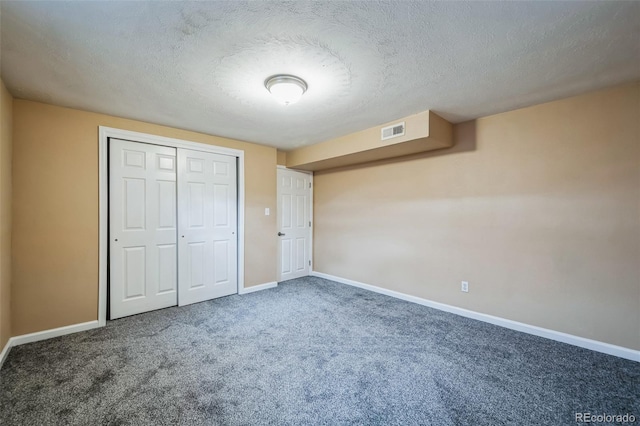 unfurnished bedroom with a textured ceiling, a closet, and carpet