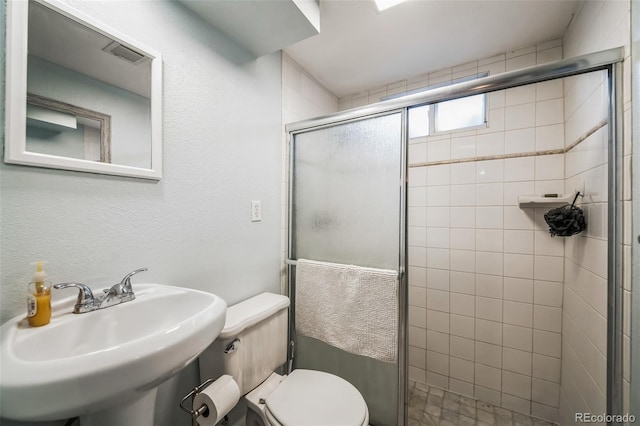 bathroom with toilet, a shower with door, and sink