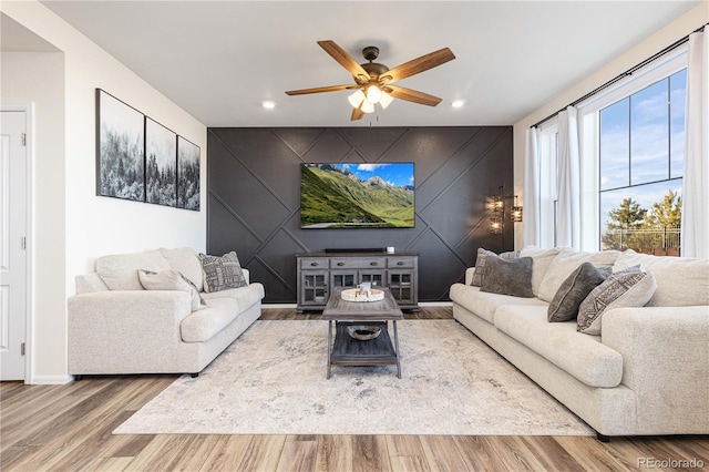 living area featuring ceiling fan, an accent wall, wood finished floors, and recessed lighting