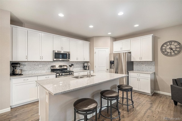 kitchen featuring stainless steel appliances, white cabinetry, hardwood / wood-style flooring, and sink