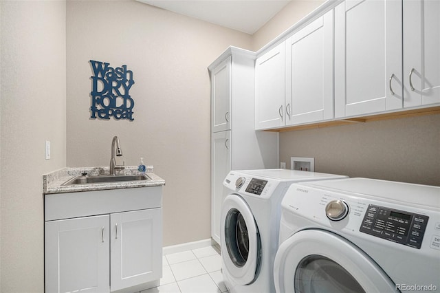 laundry room with cabinets, light tile patterned floors, separate washer and dryer, and sink