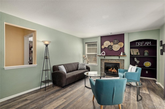 living room featuring built in shelves, a textured ceiling, a fireplace, and hardwood / wood-style floors