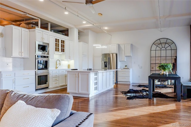 1555 California St Unit 605, Denver, CO 80202 - kitchen featuring appliances with stainless steel finishes, open floor plan, light wood finished floors, white cabinetry, and a kitchen island