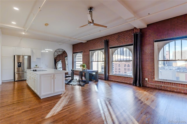 1555 California St Unit 605, Denver, CO 80202 - kitchen with stainless steel fridge with ice dispenser, brick wall, a ceiling fan, wood finished floors, and white cabinetry